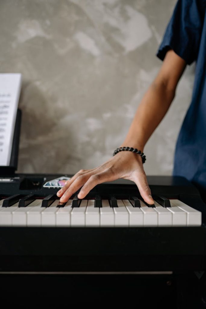 Close-up of a persons hand playing piano keys, indoor setting.